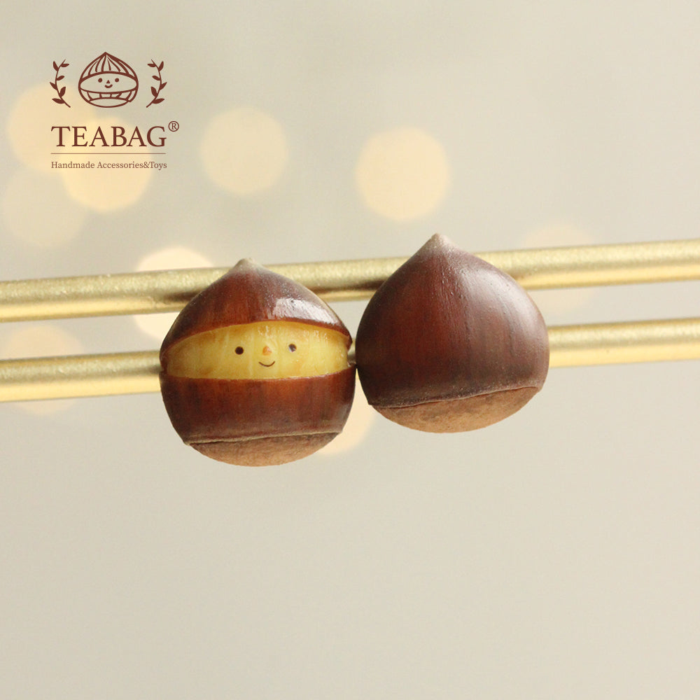 Pair of chestnut earrings displayed on gold-colored bars, showing the smiling front and brown back.