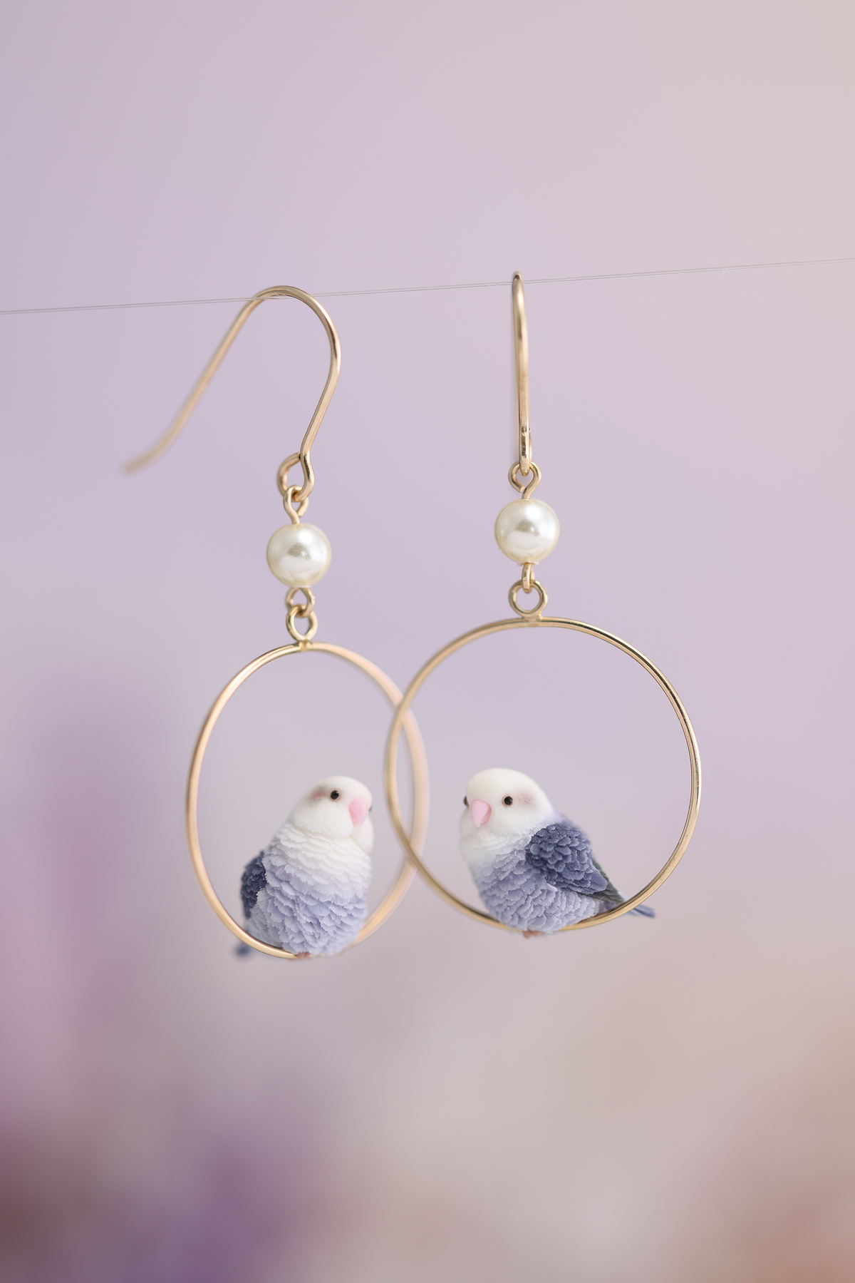 Complete pair of violet lovebird hoop earrings with pierced hooks and white beads, showing one tilted-head bird and one side-facing bird.