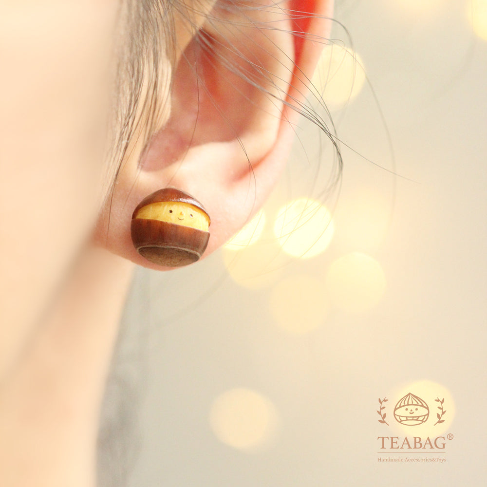 Smiling chestnut earring worn on an earlobe, showing the front face.