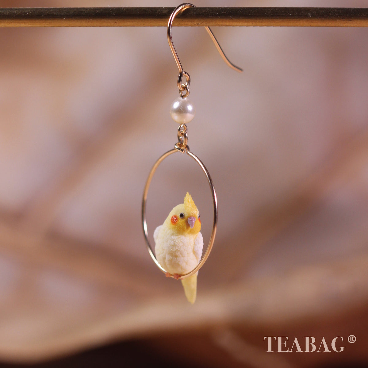 Front view of one cockatiel hoop earring with its complete pierced hook and white pearl.