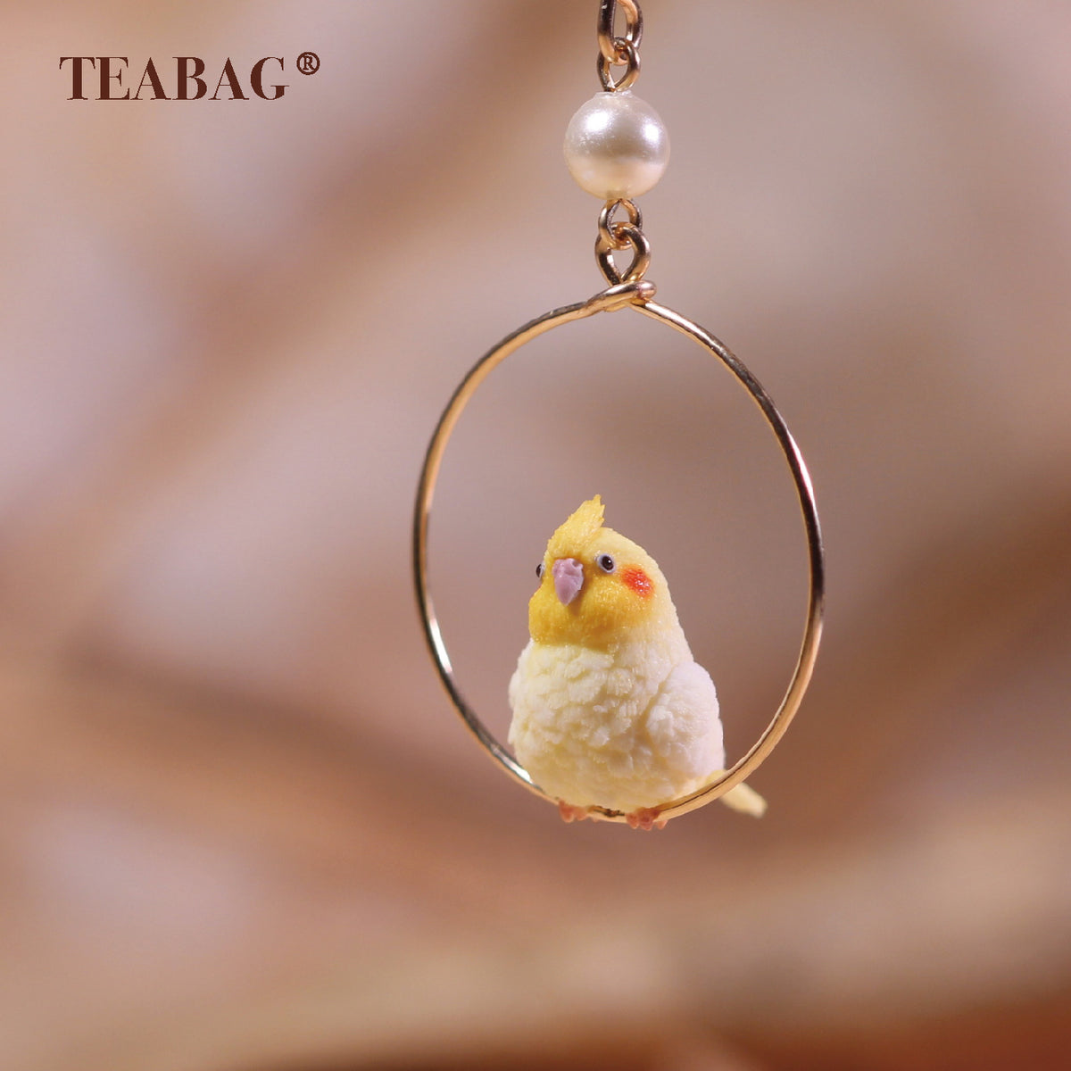 Close-up of the cockatiel bird, round hoop and white pearl; the upper fitting is outside the frame.