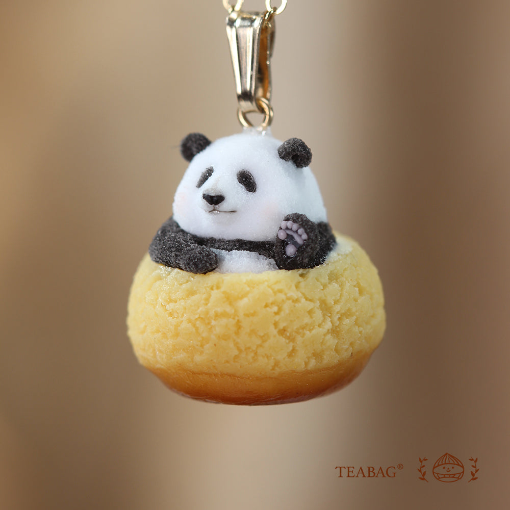 Close-up of the waving panda necklace pendant, showing its raised paw, textured cream puff and pendant bail, with TEABAG branding.