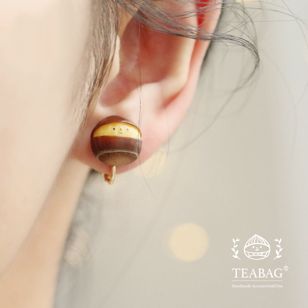 Smiling chestnut clip-on earring worn on an earlobe, with the lower clip fitting visible.