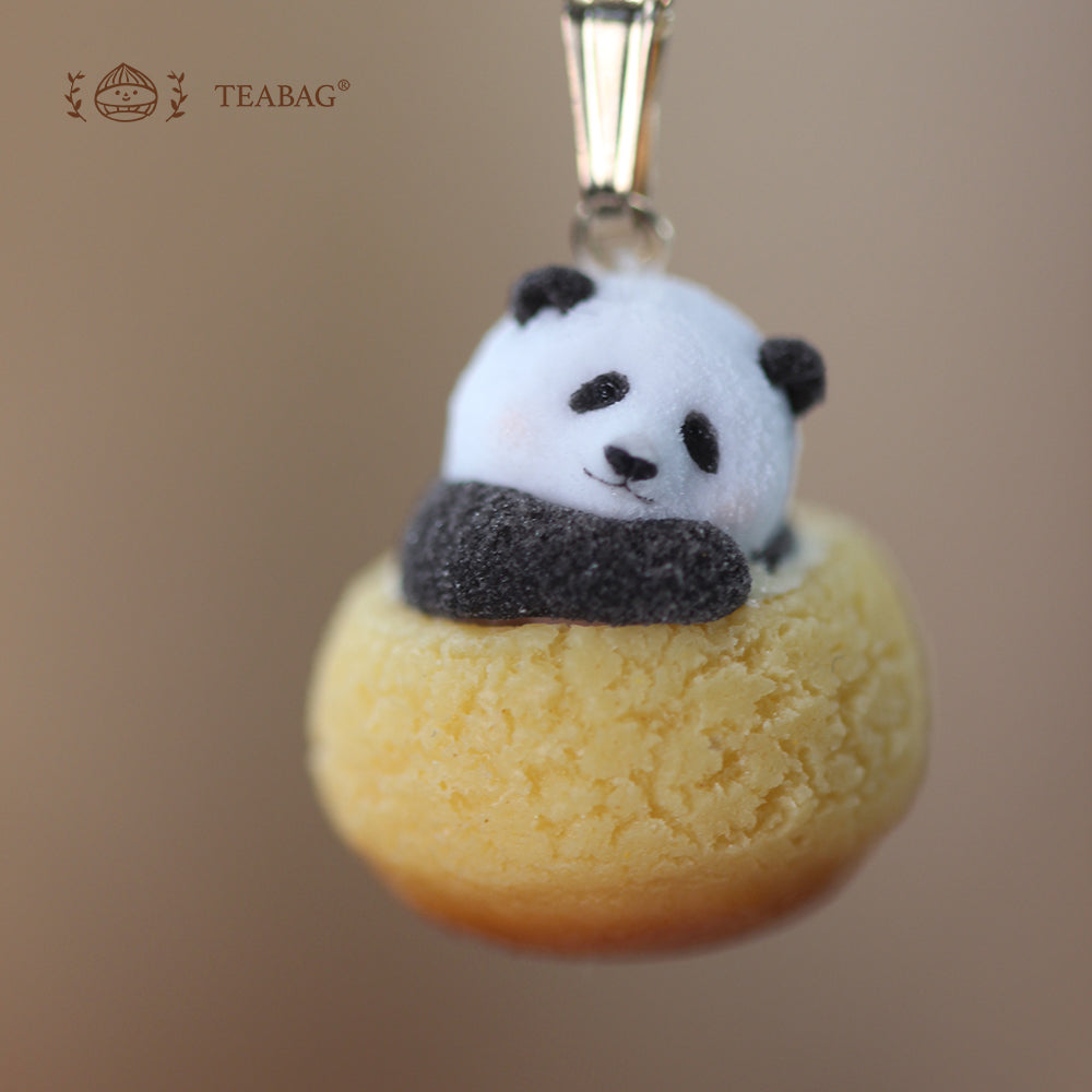 Close-up of the Resting panda cream puff necklace pendant, showing its tilted head, folded paws, textured pastry and connecting bail, with TEABAG branding.