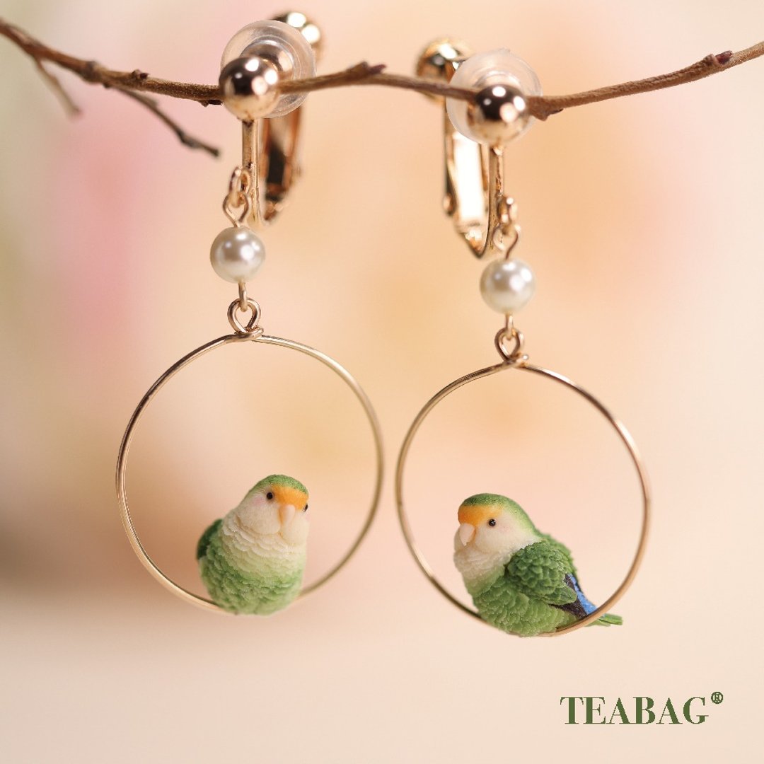 Pair of green lovebird hoop earrings with gold-colored clip-on fittings.