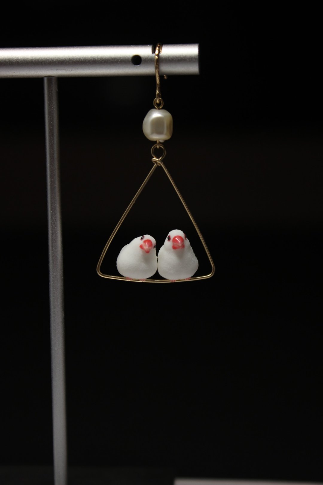 Two white Java sparrows with red beaks perched together on one triangular earring.