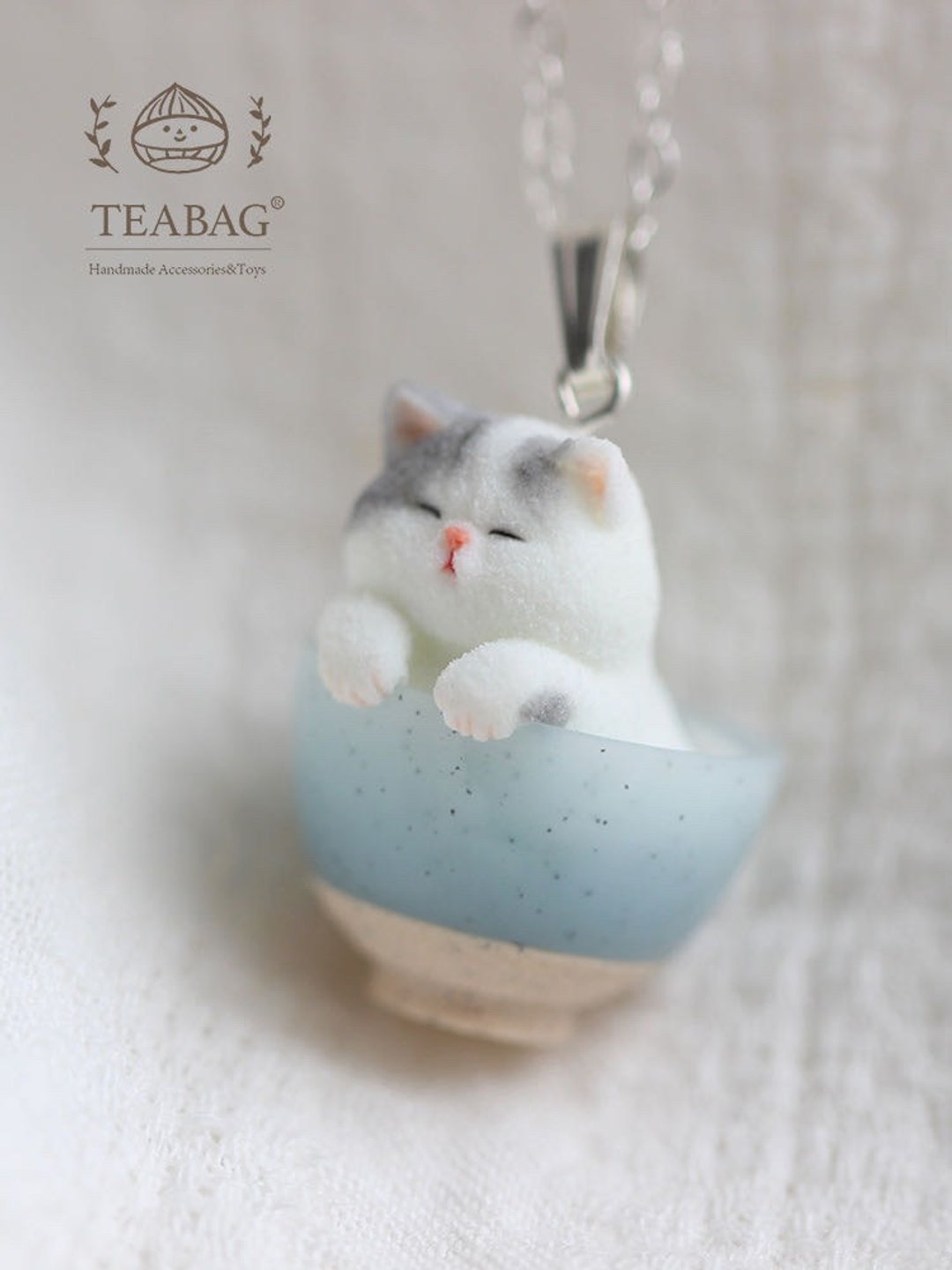 Close-up of the kitten pendant and its silver-colored bail above the cat's head.