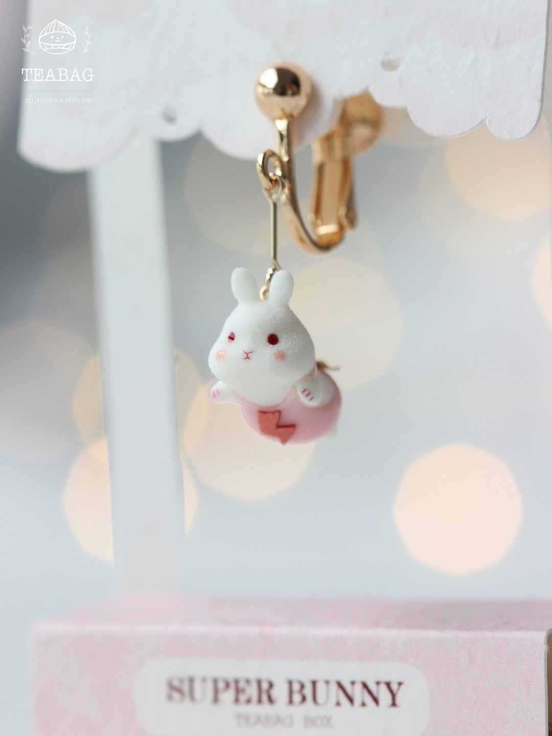 Close-up of the short clip-on flying-bunny earring on a display card.