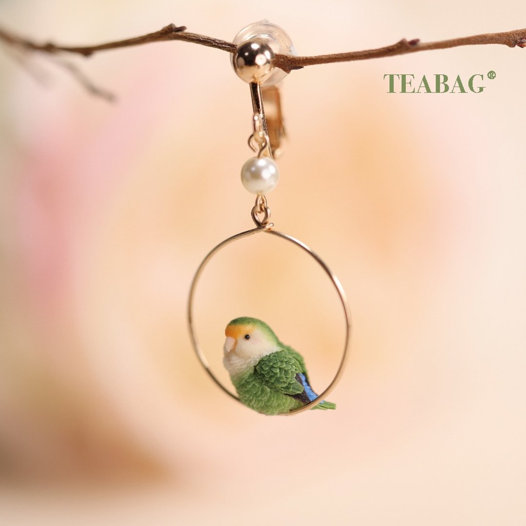 Single lovebird clip-on earring with a tiny green bird inside a round hoop.