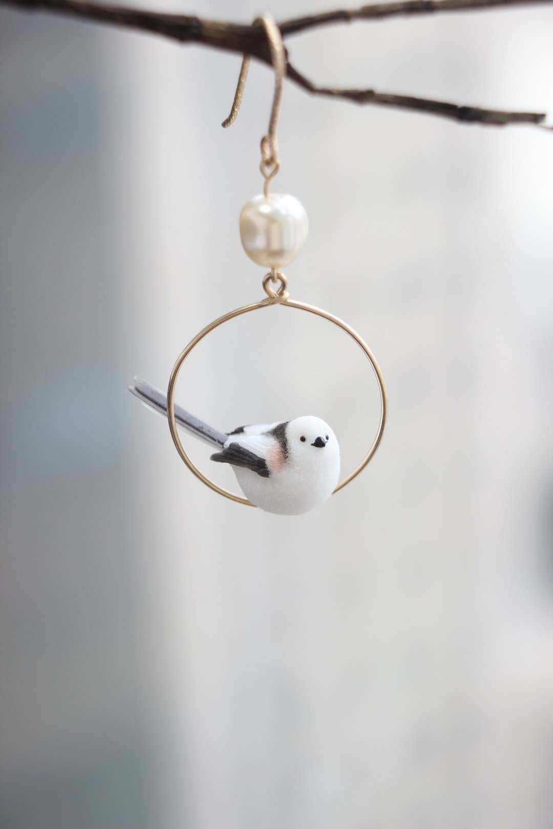 Side view of a long-tailed tit inside a round hoop, showing its black-and-white tail.