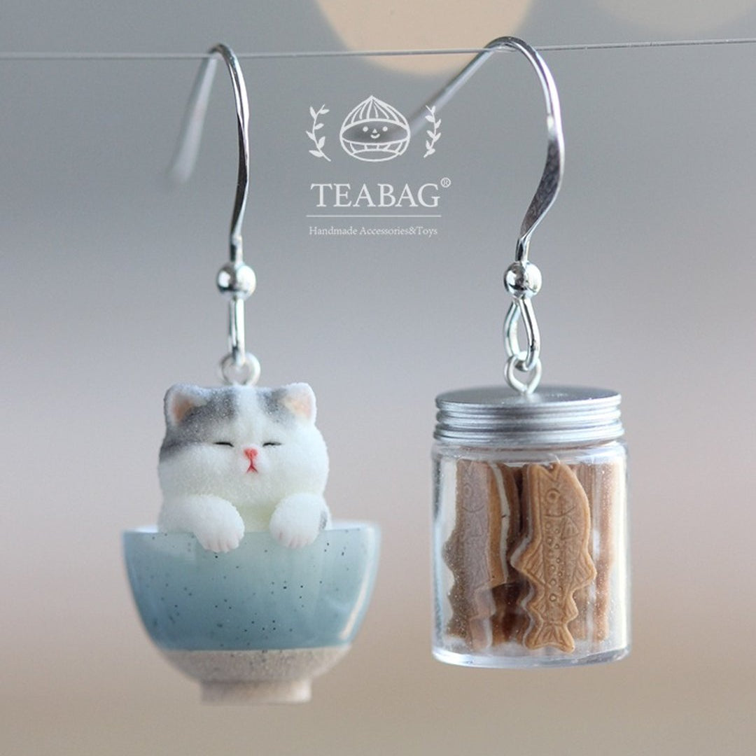 Kitten Bakery hook earrings with a grey-and-white cat in a blue bowl and a miniature cookie jar.