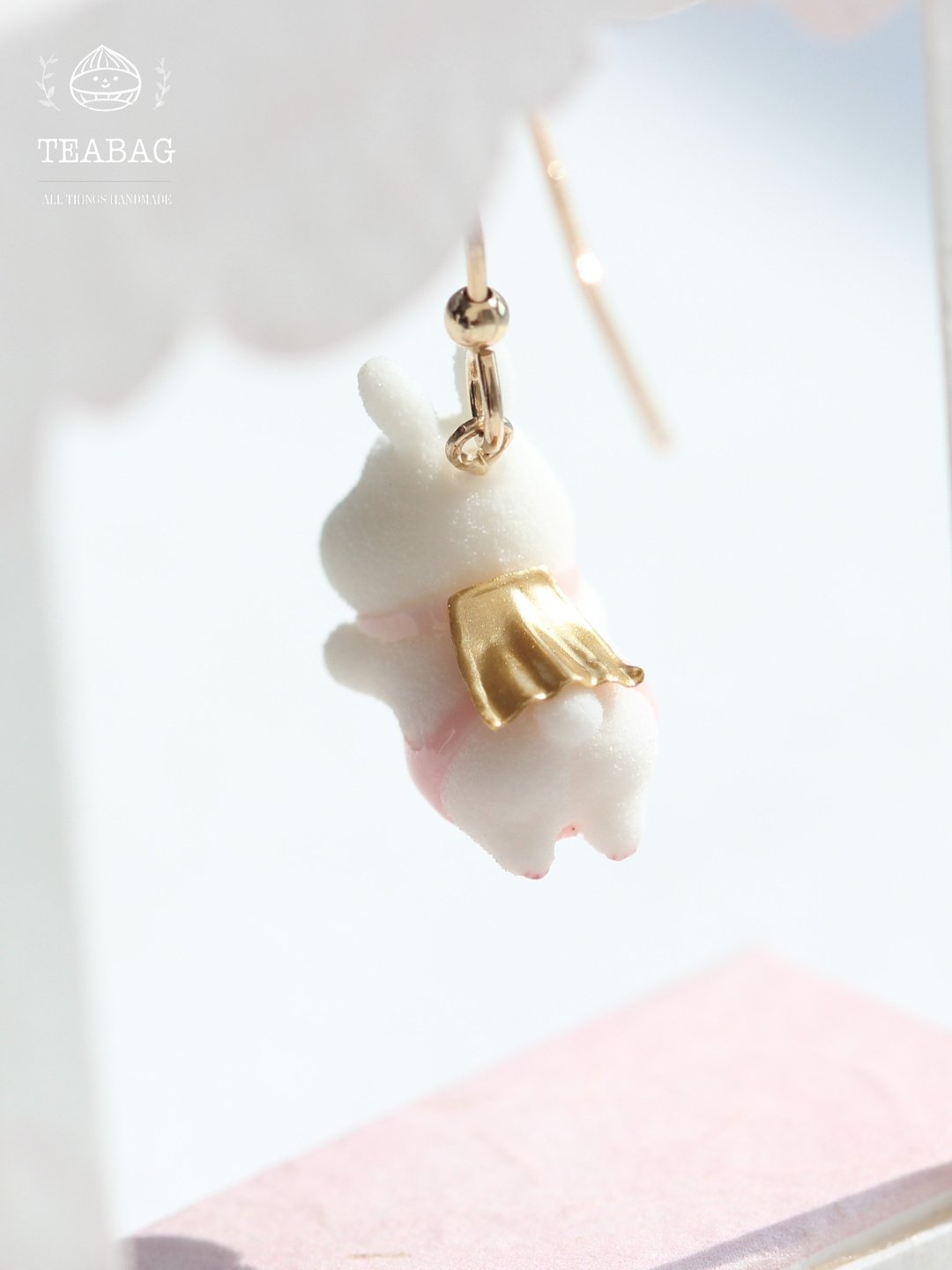 Back of the flying-bunny earring, showing the golden cape over its pink outfit.