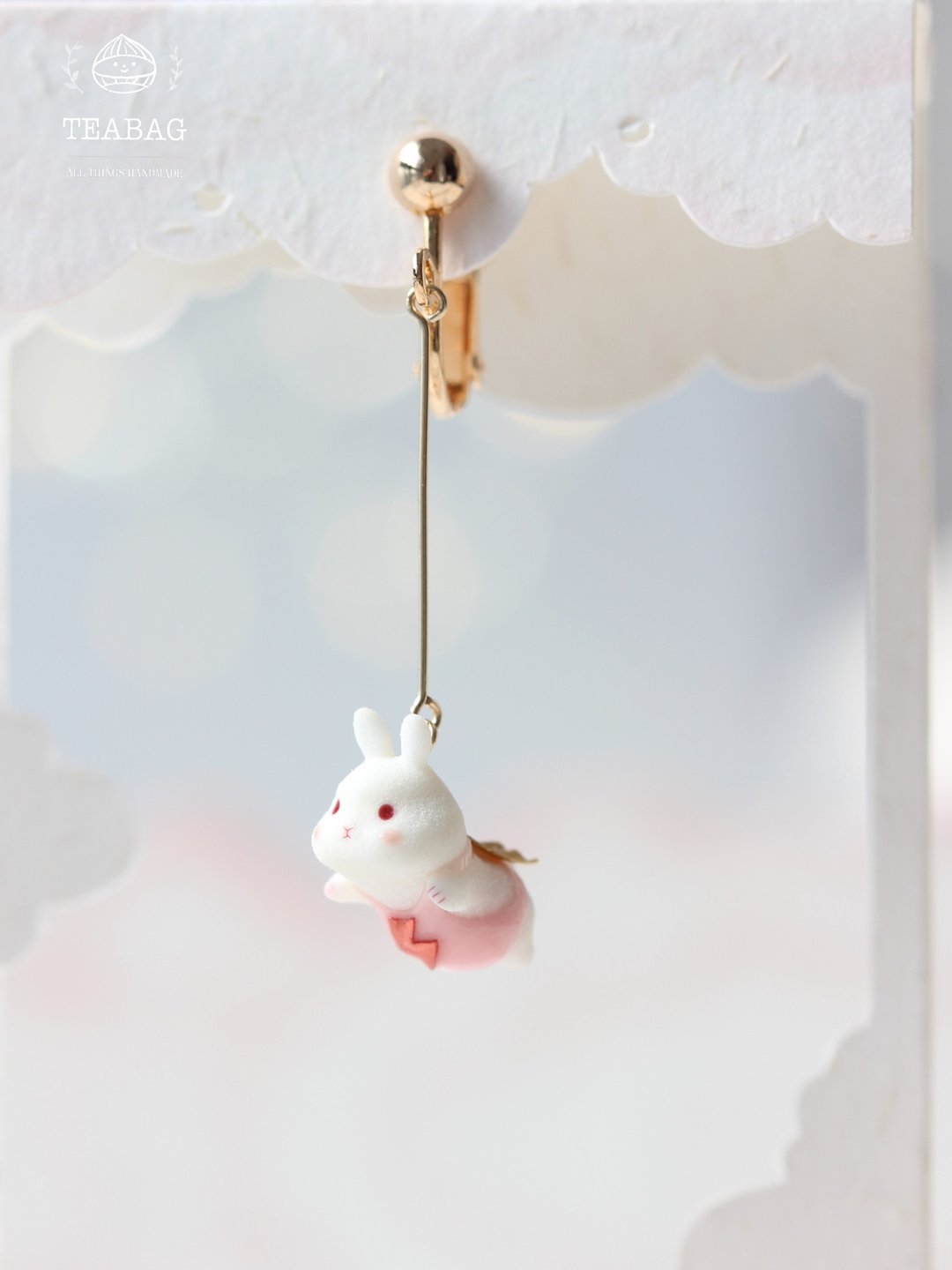 Flying-bunny clip-on earring suspended from the long straight extension.