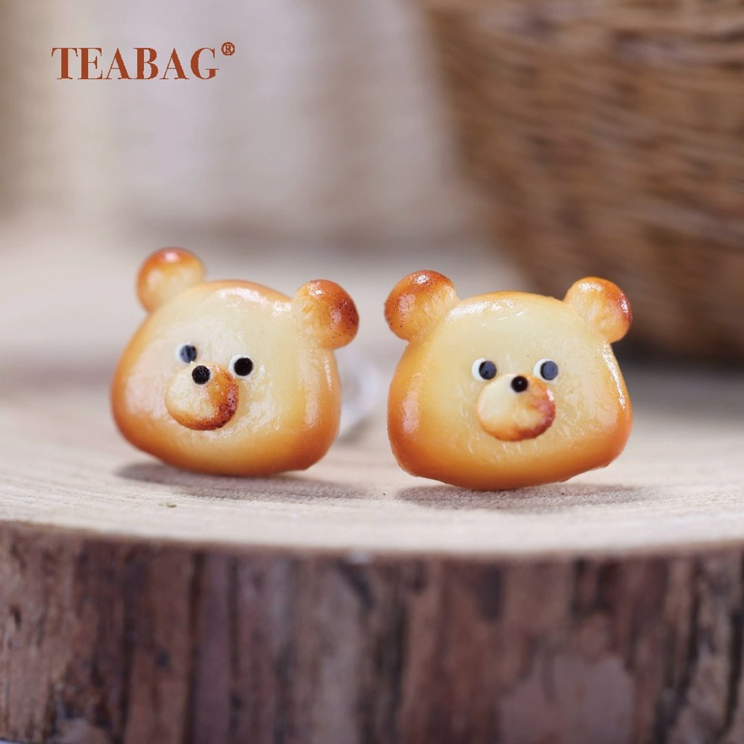 Pair of golden-brown bear bread earrings with smiling faces and rounded ears.