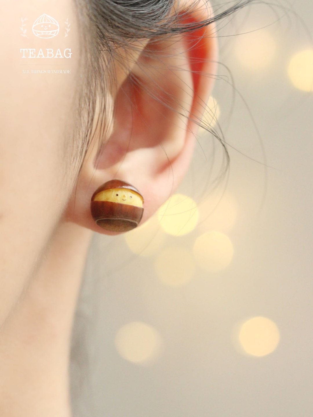 Close-up of a smiling chestnut earring worn against the earlobe.