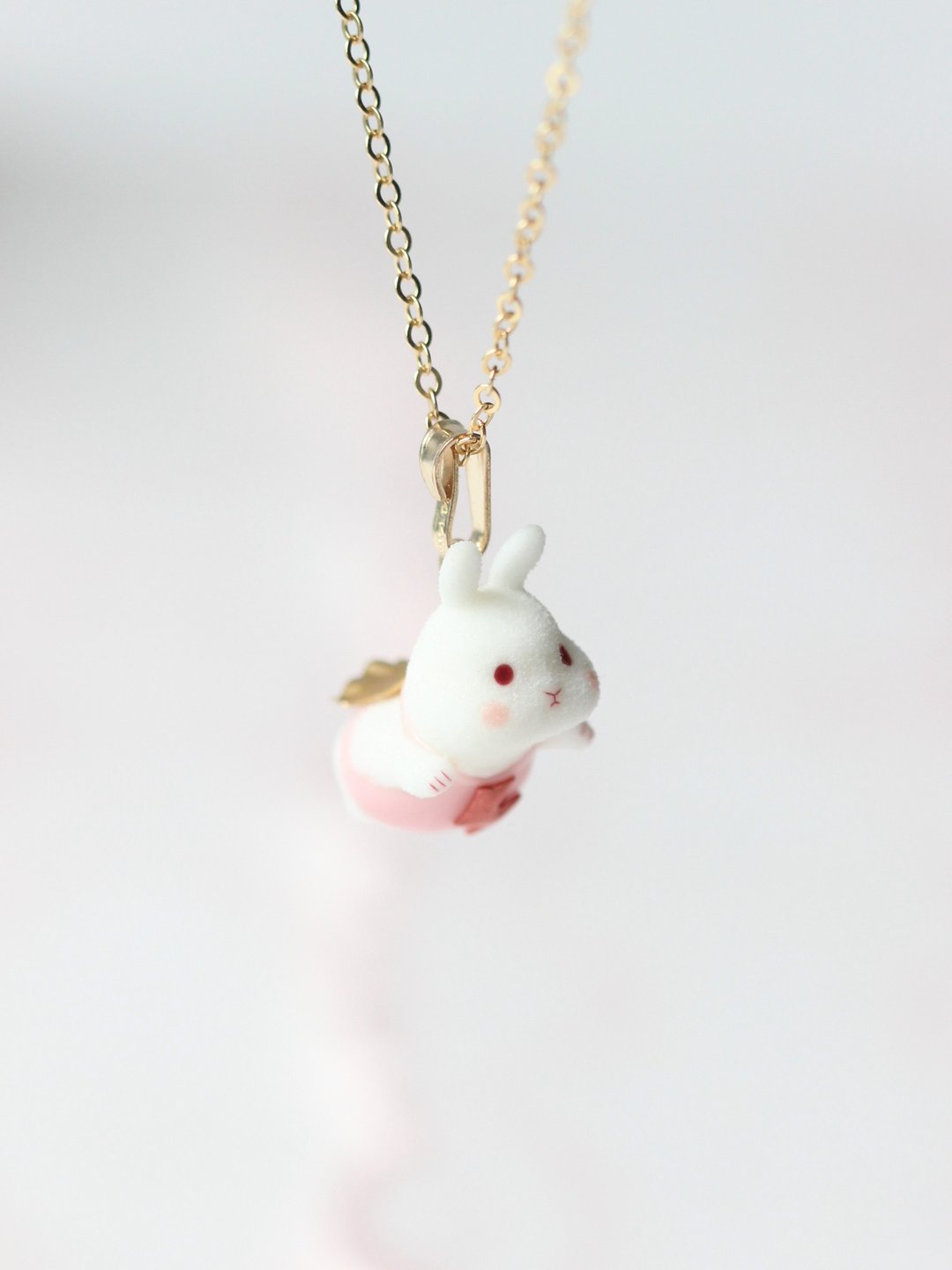Front view of the flying-bunny necklace, with the tiny rabbit hanging below its bail.