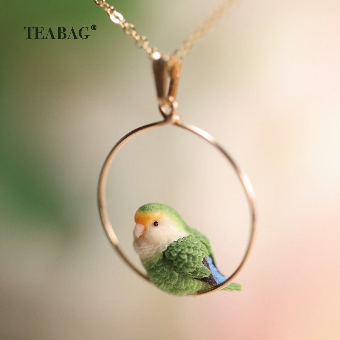 Close-up of the green lovebird inside its round pendant hoop.