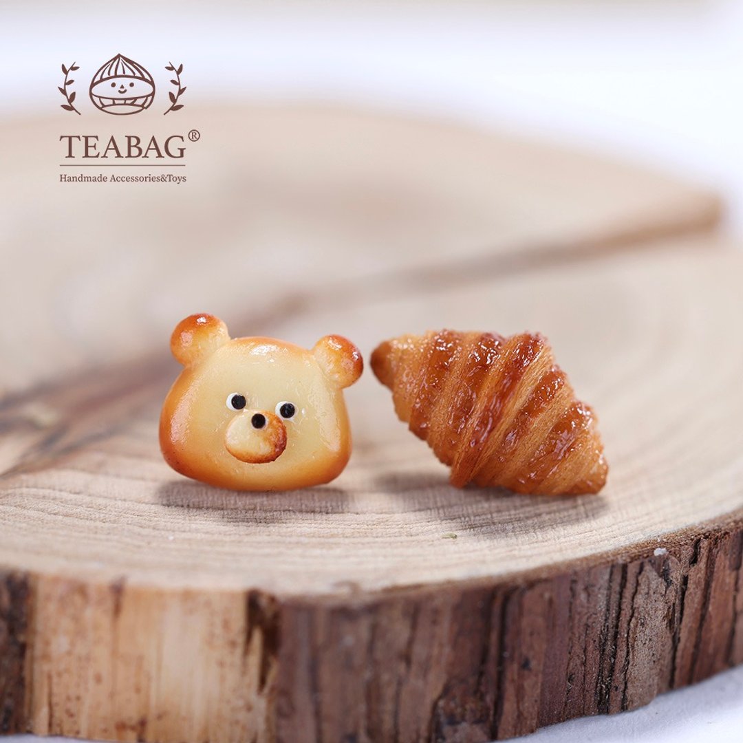 Bear bread charm beside a croissant design in a bakery collection styling photo.