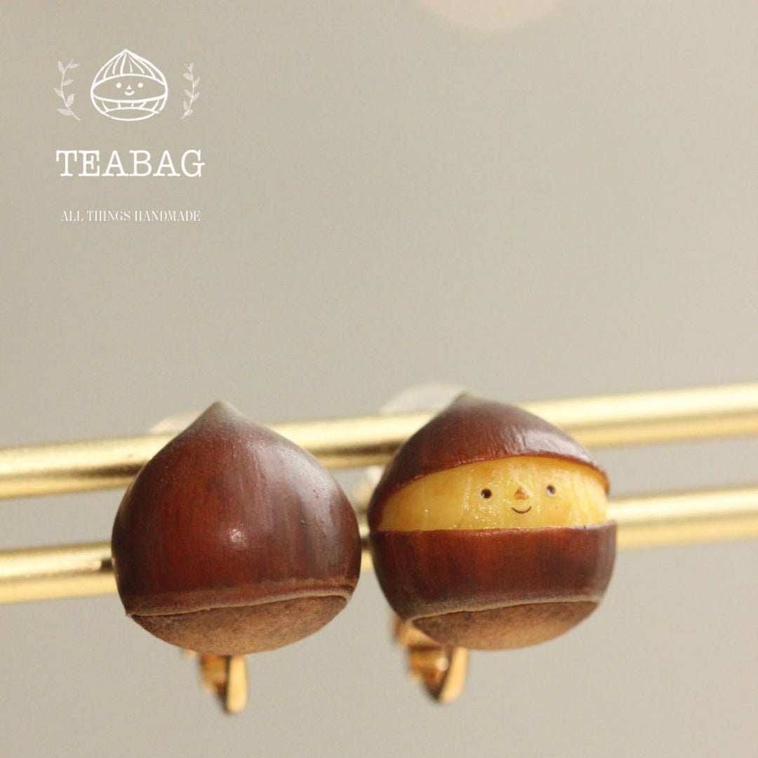 Smiling chestnut earrings shown from the front and back on a gold-colored display rod.