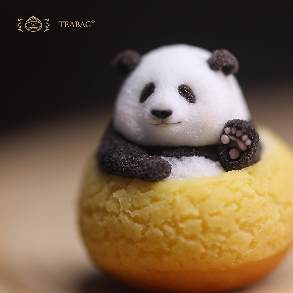 Close-up of the waving Panda Cream Puff miniature, showing the raised paw and textured pastry with TEABAG branding.